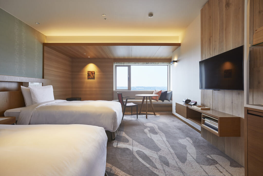 une chambre d'hotel avec deux grands lits, de la moquette grise et des murs en bois