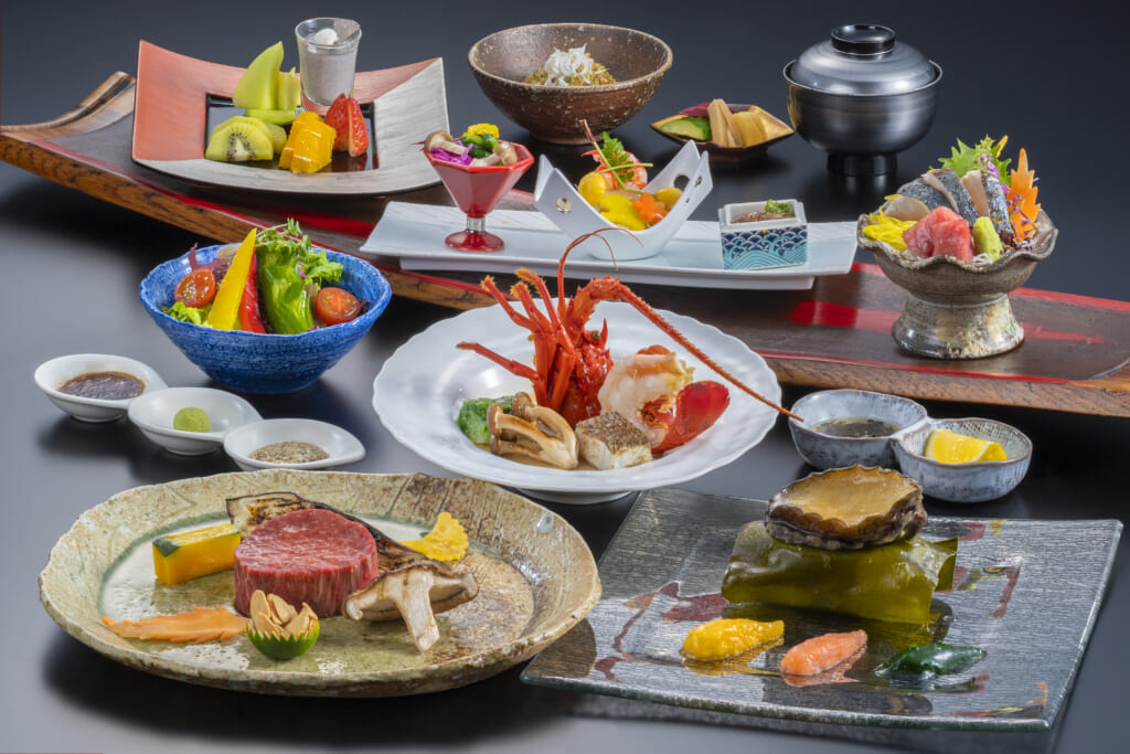 Une grande variété d'aliment crus et très colorés sont présentés dans différentes assiettes : des coquillages, un écrevisse, un morceau de boeuf, des sashimis, des légumes et des fruits.