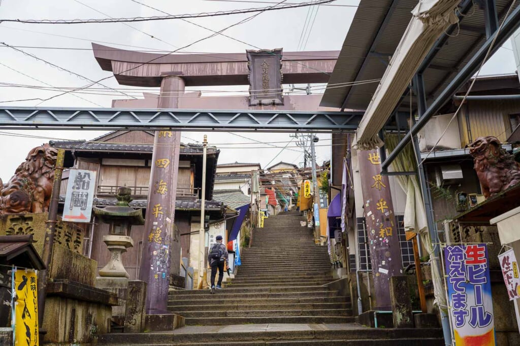 Commerces japonais le long d'un grand escalier surmonté d'une porte torii