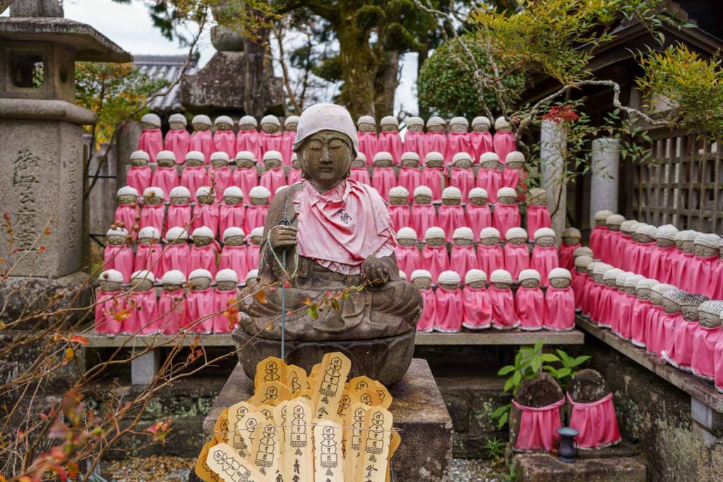 De petites statues vêtues de rose dans un temple japonais