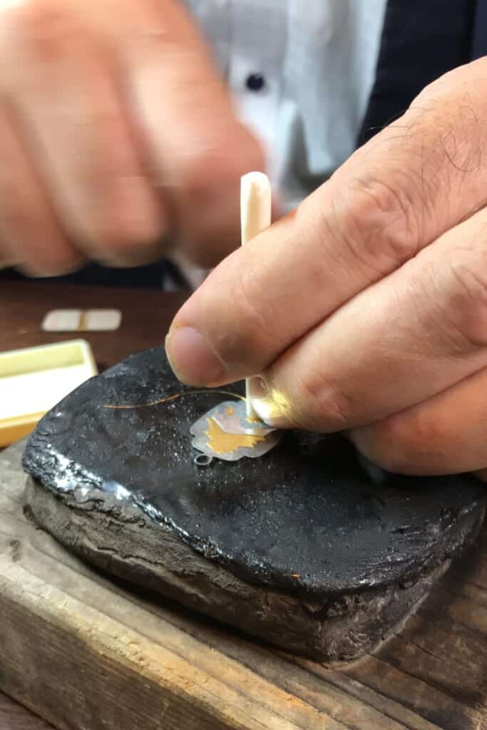 un artisan japonais incruste minutieusement un pendentif
