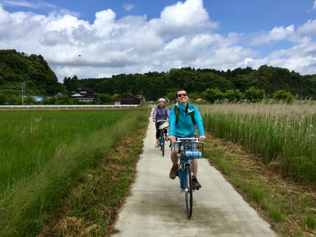 personnes à vélo sur un chemin au milieu de champs de blé