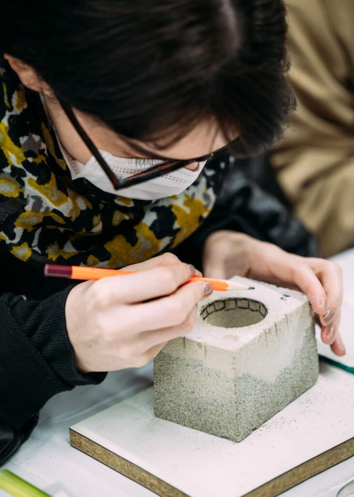 Une femme grave des motifs à l'intérieur d'un moule servant à créer un objet en étain