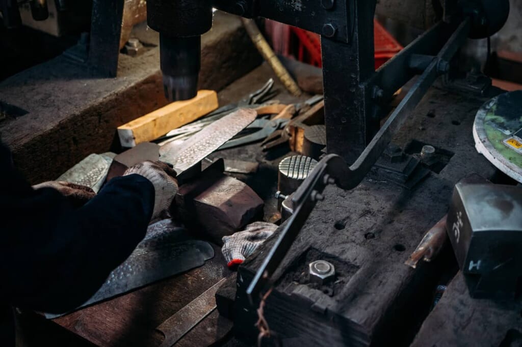 un artisan japonais en train de forger la lame d'un couteau