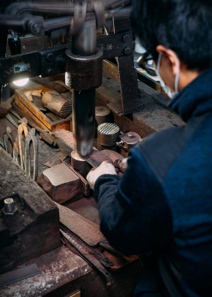 Un artisan japonais en train de travailler sur la lame d'un couteau
