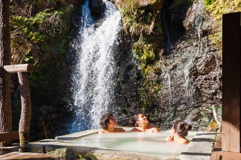 trois personnes dans un bain japonais onsen en plein air