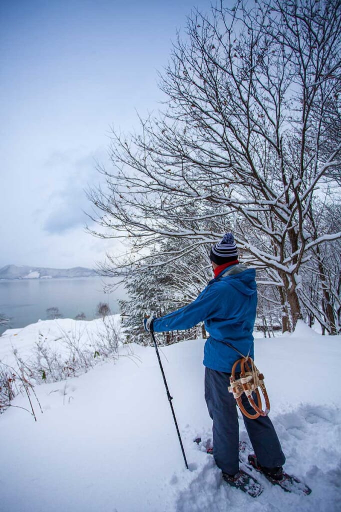 Un visiteur admire le lac Tazawa depuis ses rives enneigées