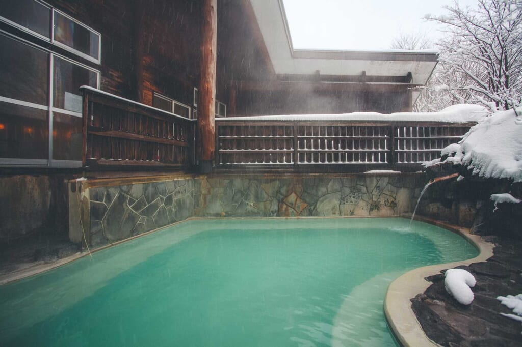 Les eaux turquoises d'un bain thermal japonais en hiver à Tazawako