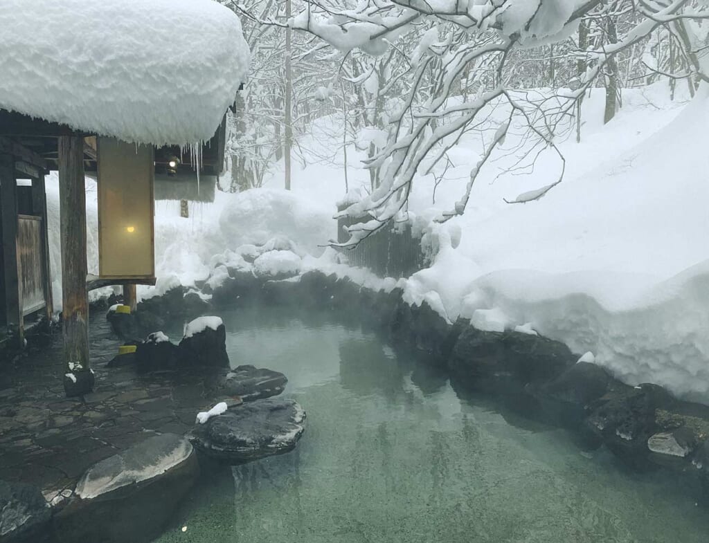 Un bain d'eau thermale au Japon entouré de neige dans la préfecture d'Akita
