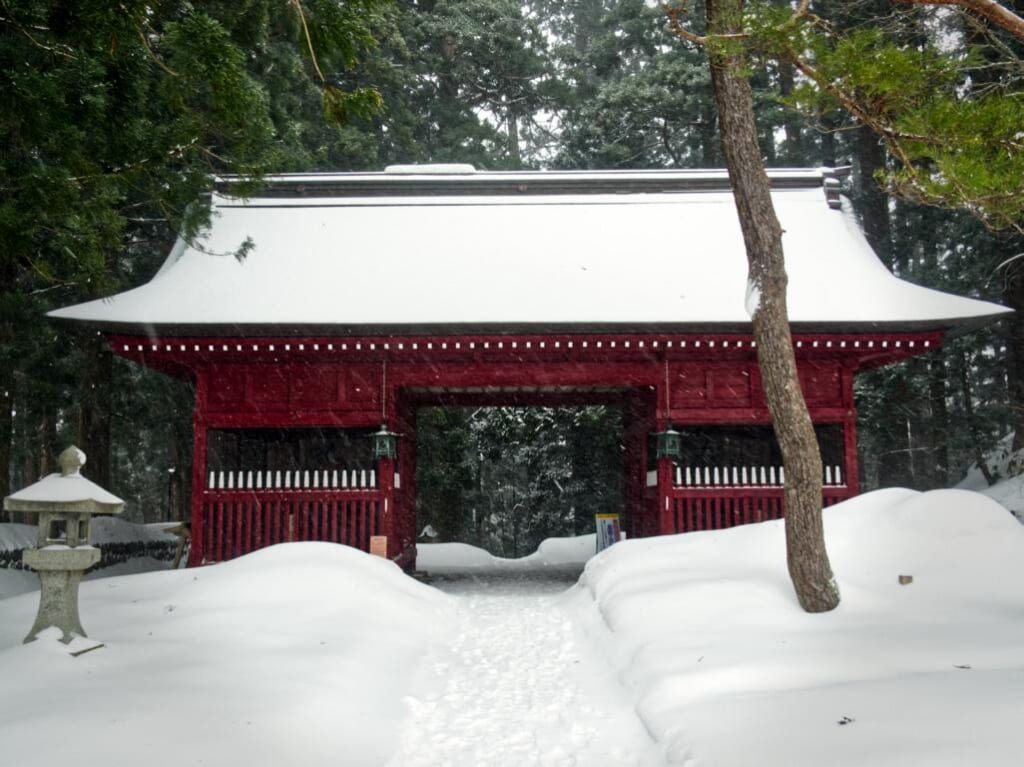 Une grande porte rouge dans une forêt enneigée au Japon