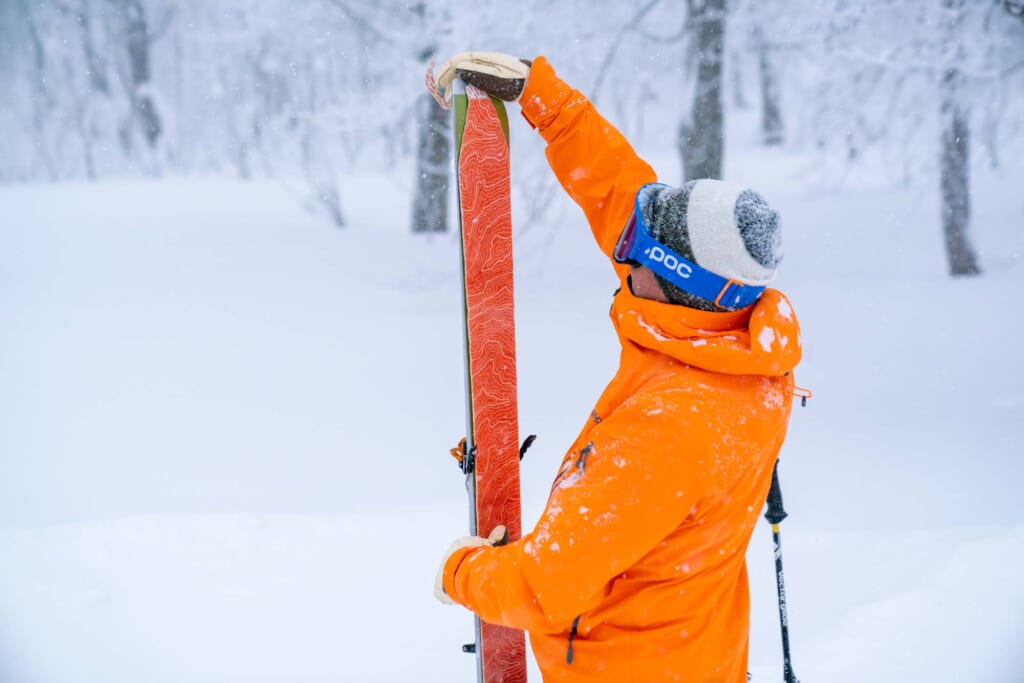 Un skieur entrain de retirer la peau de phoque d'un ski de randonnée