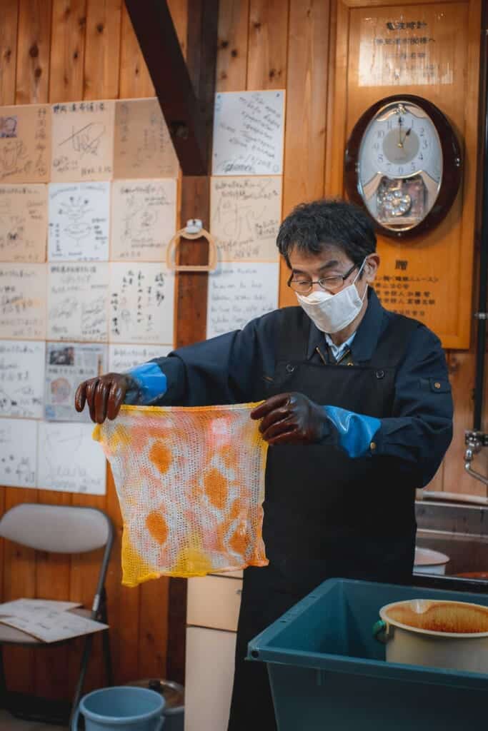 un artisan japonais en train de teindre une serviette de bain en papier washi