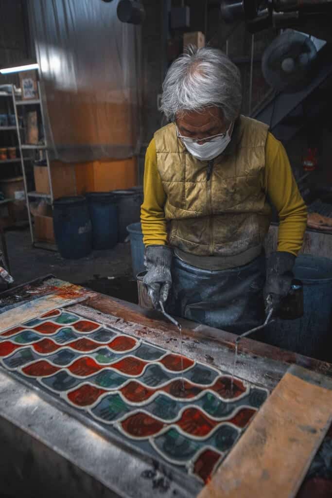 un artisan japonais en train de teindre une serviette tenugui selon des méthodes traditionnelles