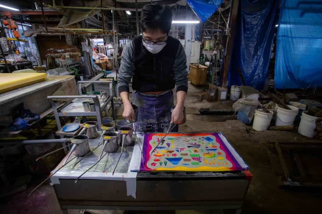 un artisan travaille sur les motifs d'une serviette tenugui artisanale