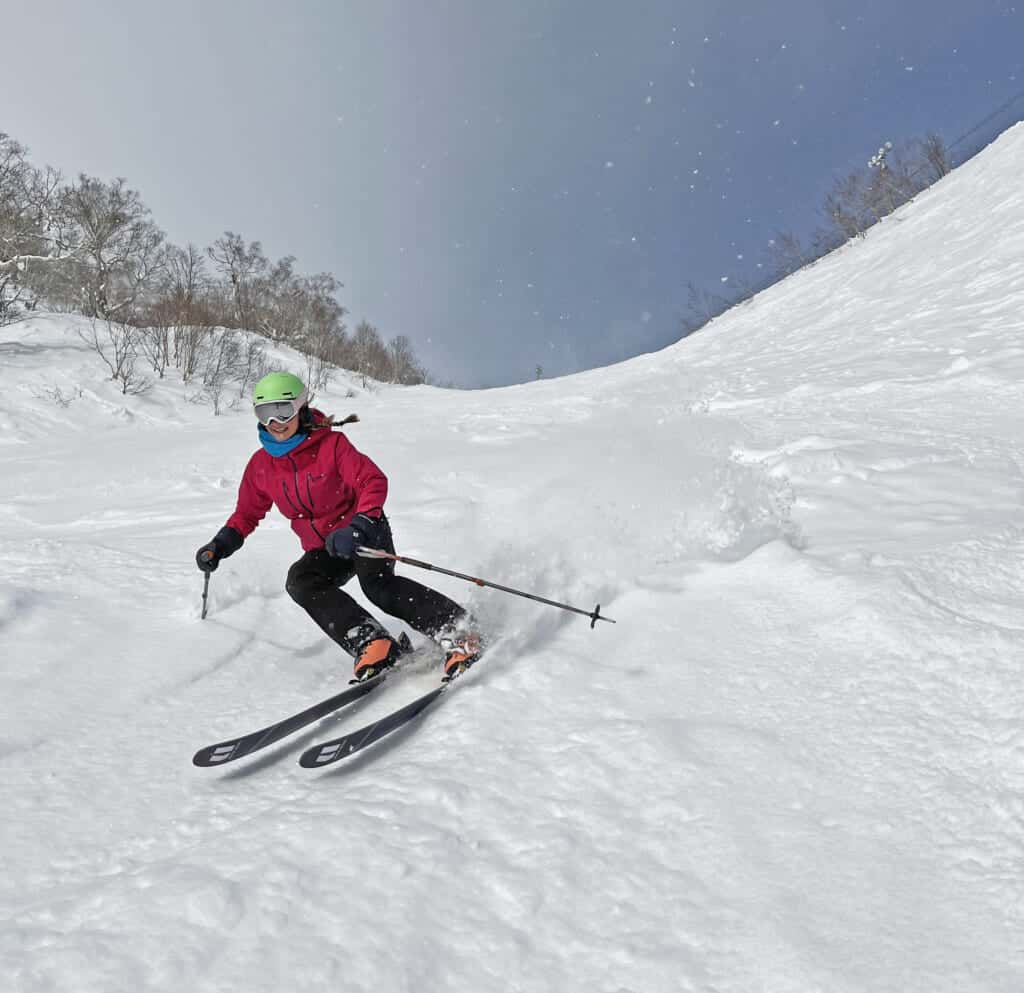 Une skieuse dévale une pente dans de la neige poudreuse au Japon