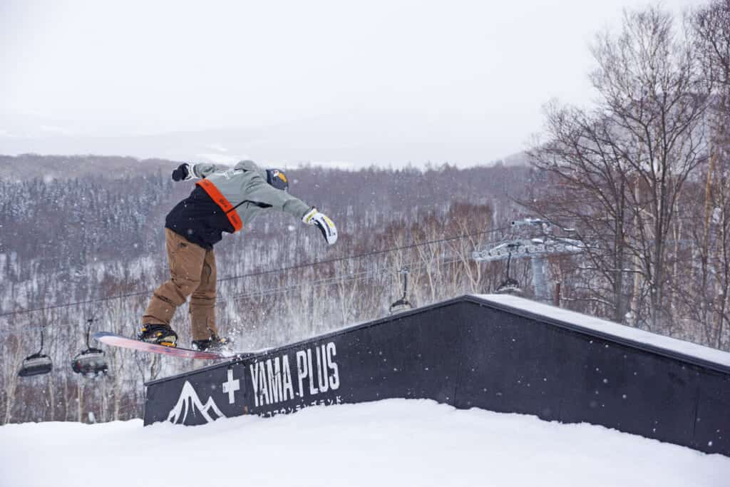 Une personne fait du snowboard sur une rampe dans une station de ski au Japon