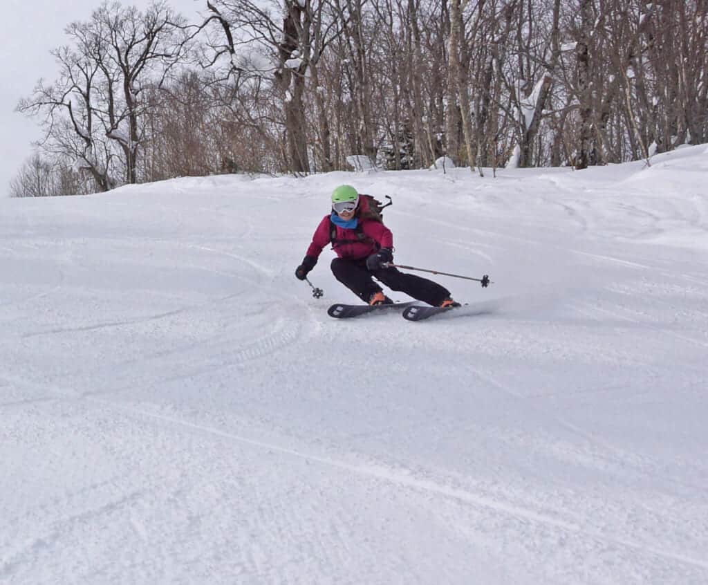 Une skieuse descend une piste de ski dans une station japonaise à Hokkaido