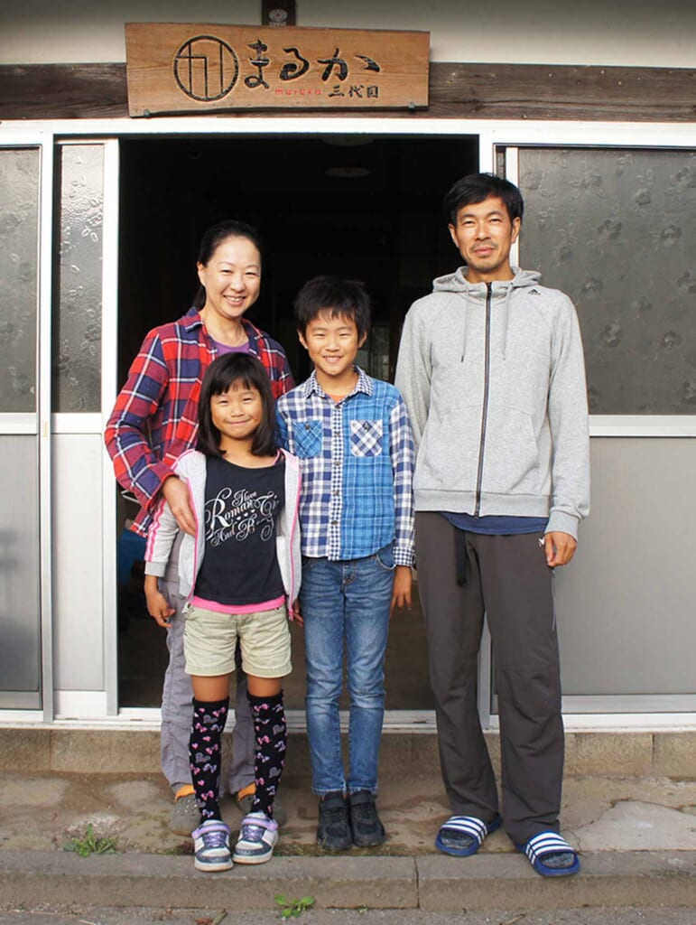 Une famille d'agriculteurs japonais devant leur maison. Parents et deux enfants.