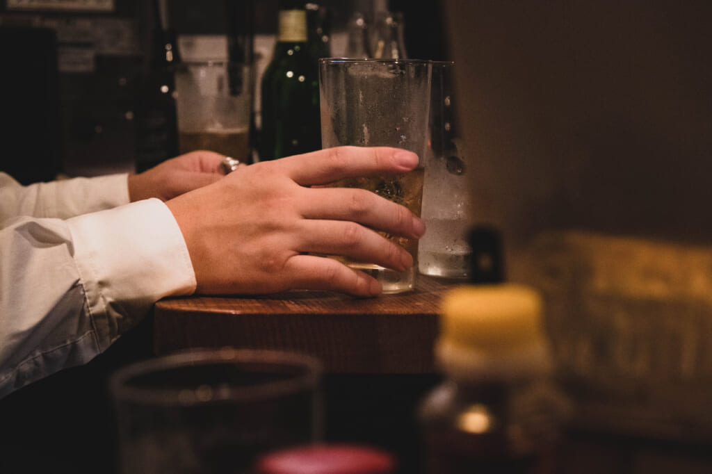 Mains d'un japonais qui tient un verre dans une izakaya