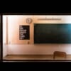 Installation d'Apichatpong Weerasethakul dans une salle de classe désaffectée avec un poster du slogan d'Okayama Art Summit 2022 "Do We Dream Under The Same Sky"