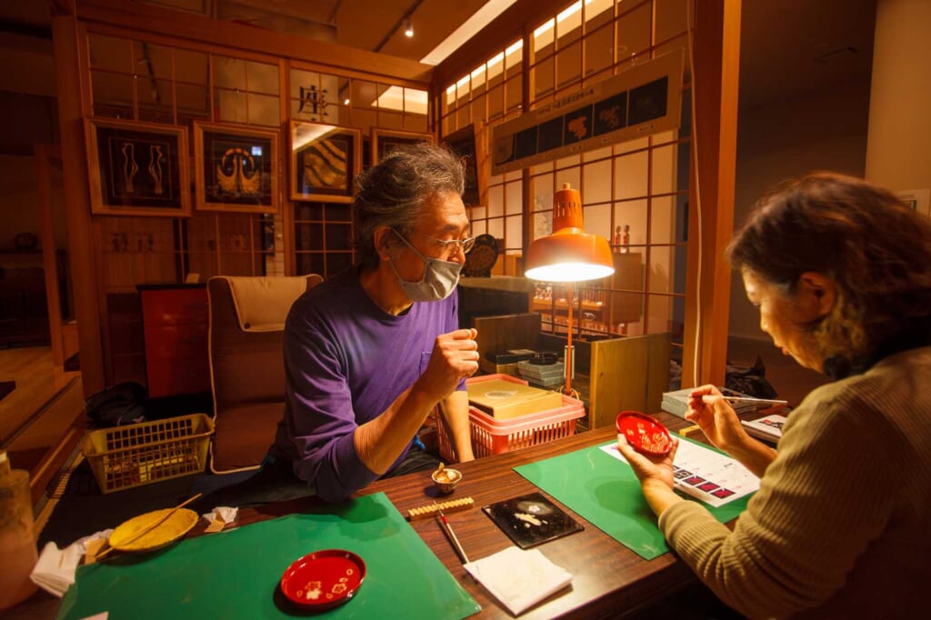 Un artisan japonais explique à une cliente comment déposer de la laque