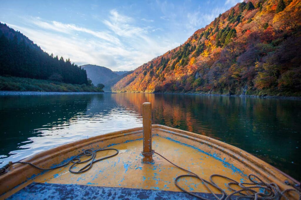 Un bateau naviguant sur un fleuve au Japon durant l'automne
