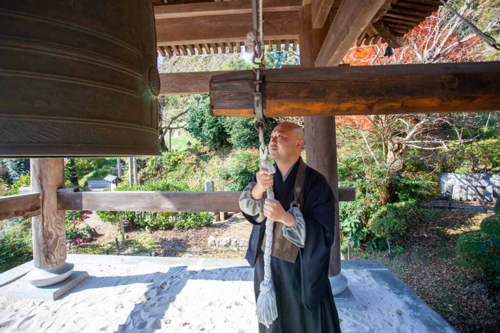 moine bouddhiste japonais faisant sonner la cloche d'un temple