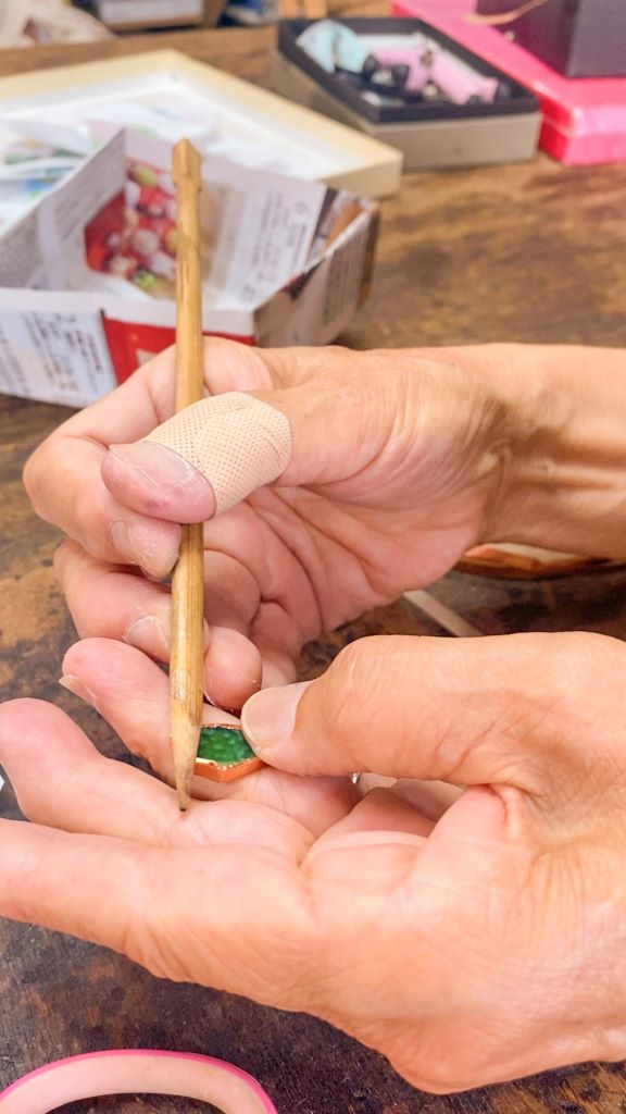 Une japonaise enserre un morceau de vitrail dans une feuille de cuivre
