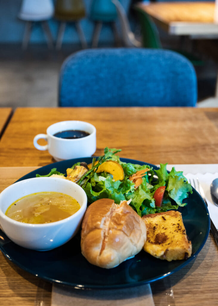 assiette avec de la salade, la soupe et du pain devant le café au petit déjeuner