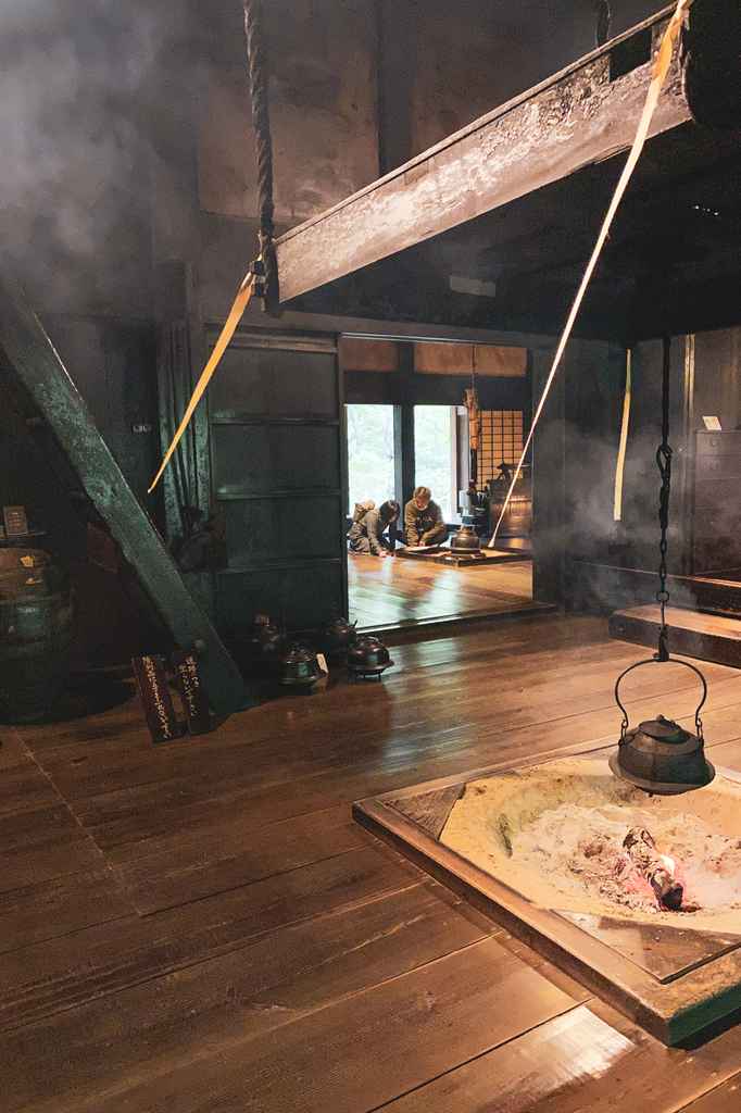 L'intérieur d'une maison traditionnelle japonaise avec un théière chauffant au-dessus du foyer central