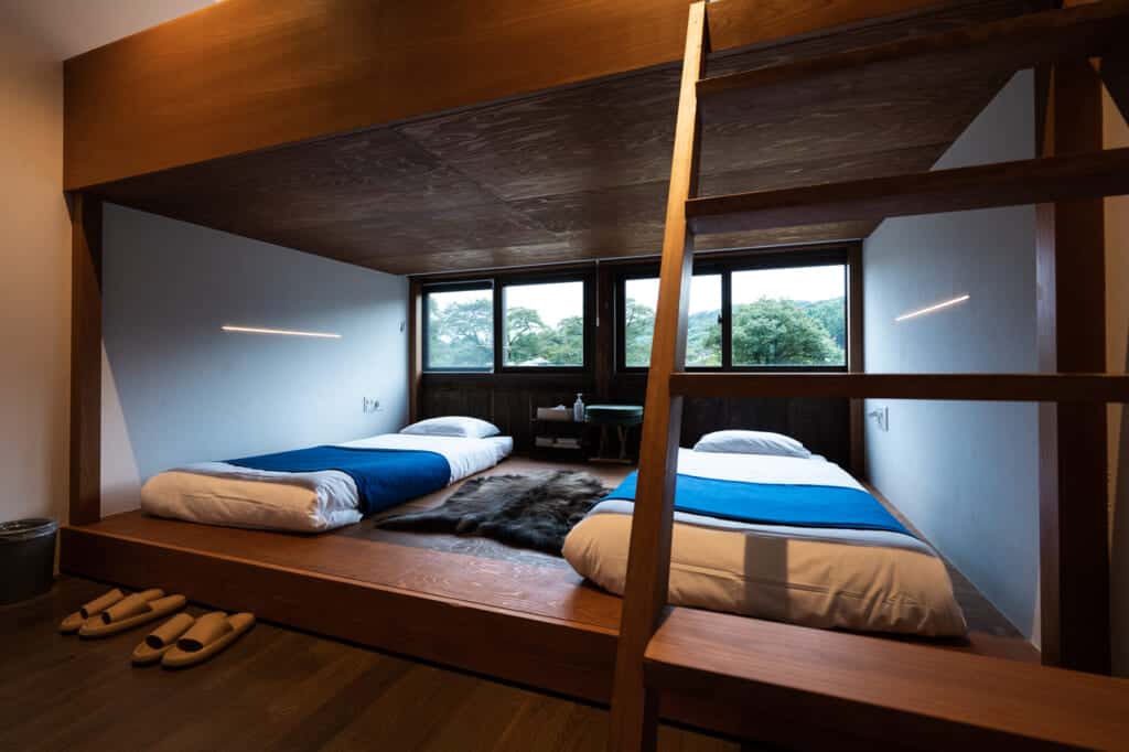 Chambre spacieuse dotée de deux lits dans une ancienne école transformée en hébergement de tourisme durable au Japon