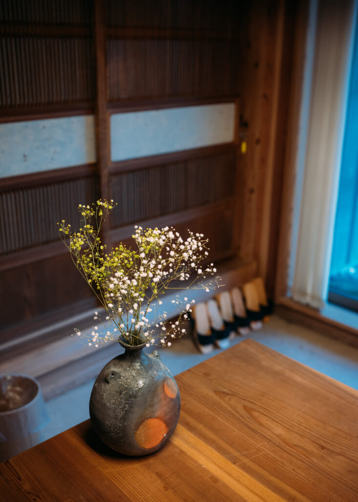 Un vase avec des fleurs posé sur une table en bois dans un hôtel au Japon