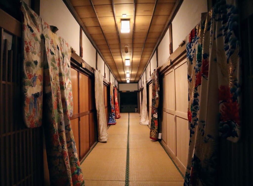 Couloir d'auberge traditionnelle japonaise bordé de kimonos.
