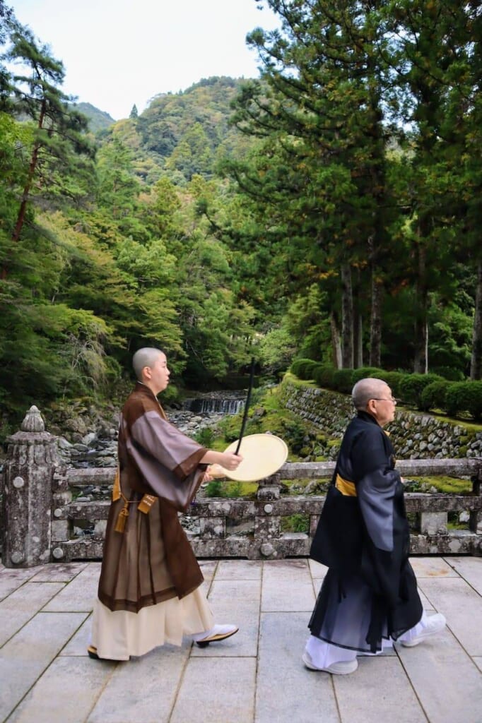 deux moines bouddhistes traversent le pont en pierre d'un temple