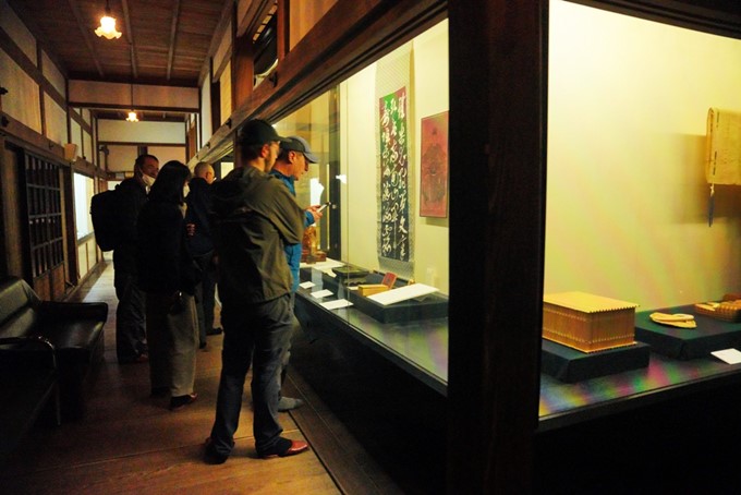 Des visiteurs dans un musée japonais devant des calligraphies et autres objets historiques