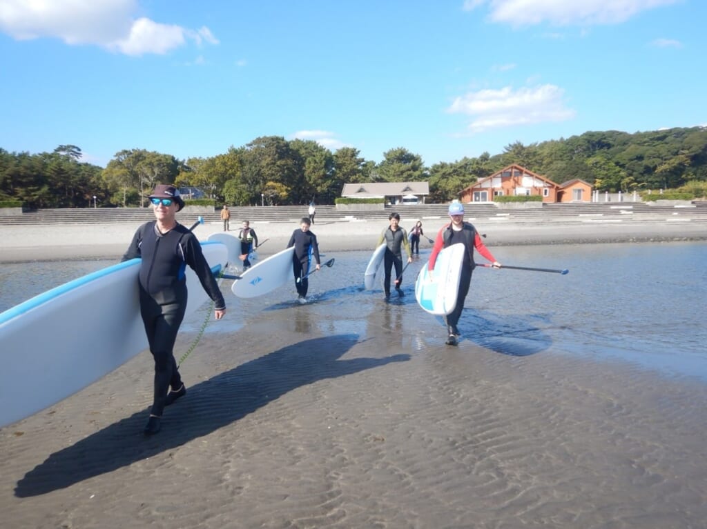Des voyageurs avec des plances de SUP sur une plage au Japon