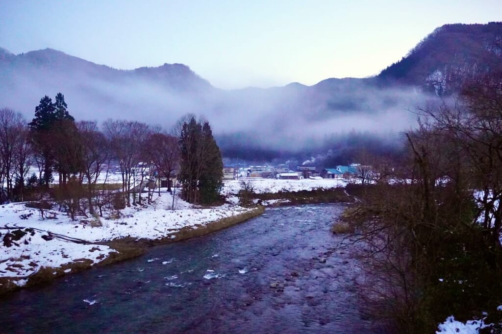 paysage de neige au bord d'une rivière vu du train sur la ligne Akita Nairiku