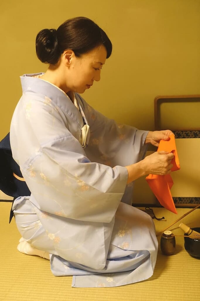 Mika pliega y despliega varias veces el fukusa durante el taller de la ceremonia del té en Tokio
