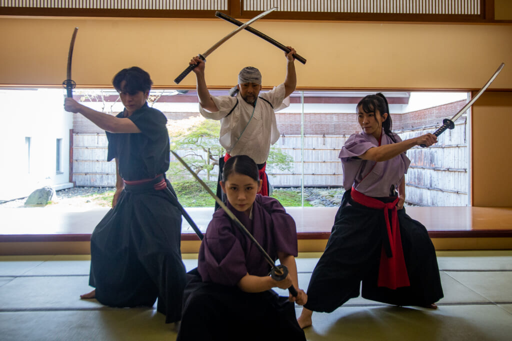 cuatro personas vestidas de samurais posando con katanas