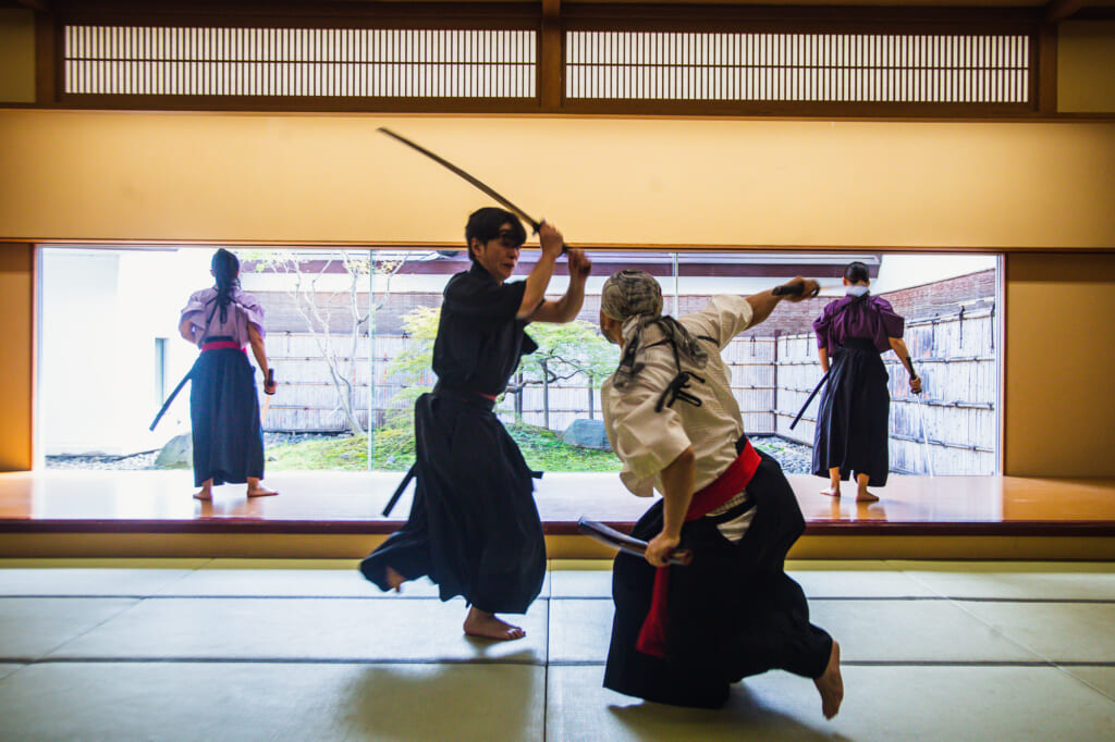 dos personas luchando con espadas samurais