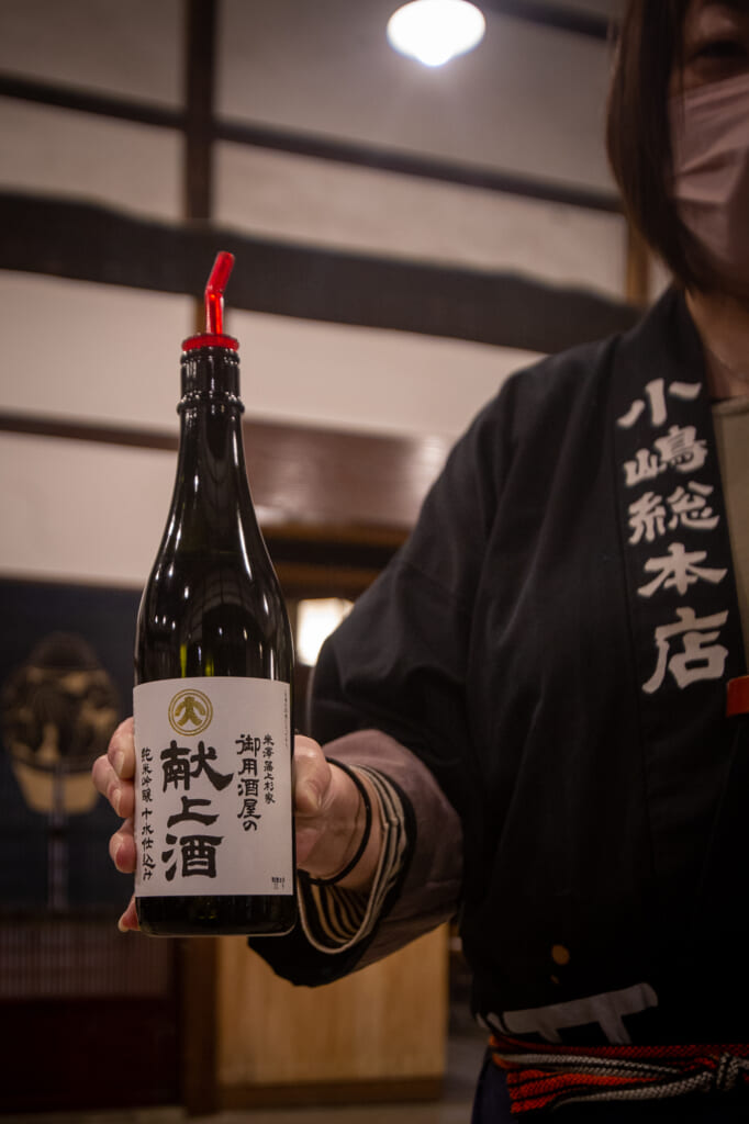 persona sujetando una botella negra de sake