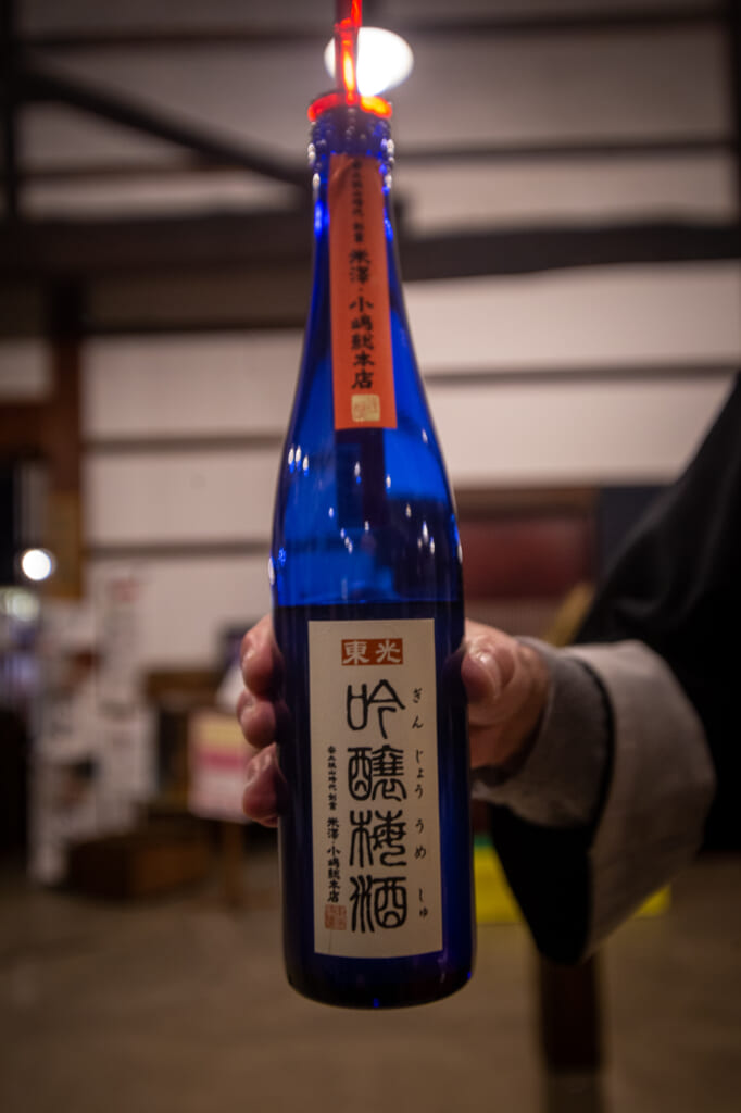 persona sujetando una botella azul de umeshu