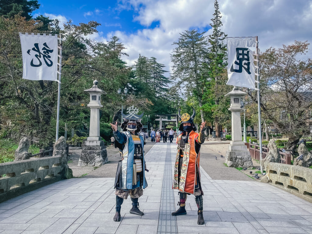 dos personas vestidas de samurai saludando a la cámara