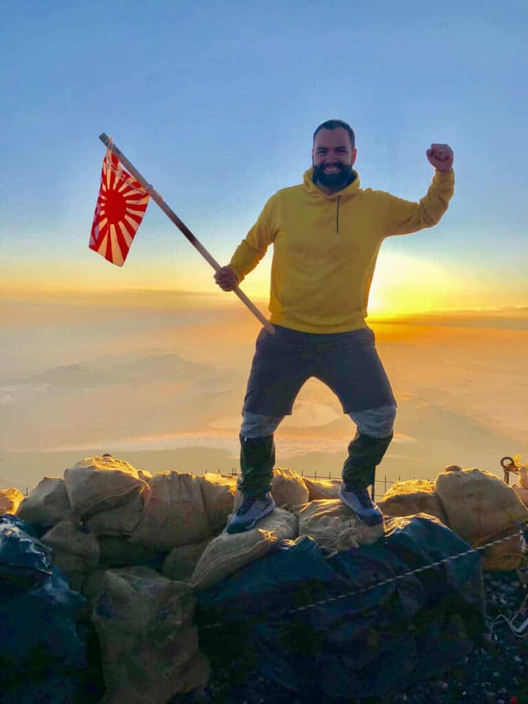 Un chico con una bandera japonesa en la cima del Monte Fuji
