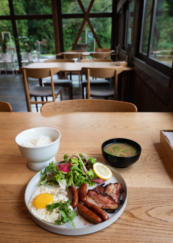 un desayuno con huevos, salchicha y sopa de miso en un alojamiento renovado en Japón