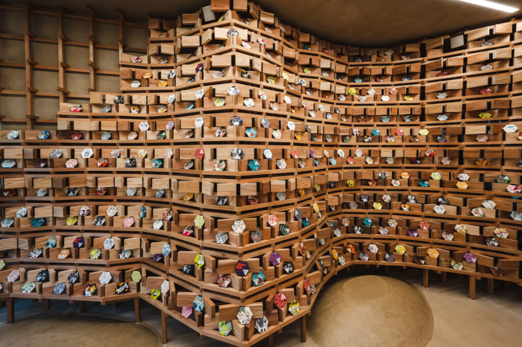 Una pared de madera con unas estanterías con piezas de cerámica en exhibición, un ejemplo de turismo sostenible en Japón