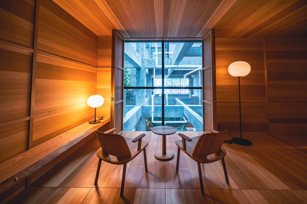 El interior del hotel Shiroiya con una pared de madera y dos sillas mirando el patio de cemento