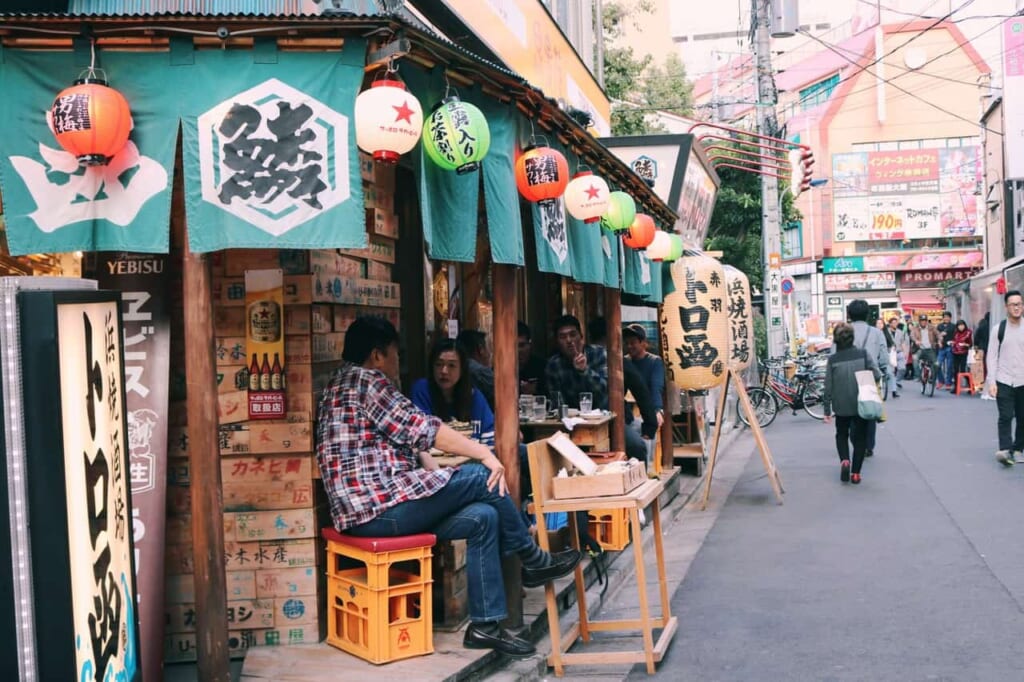 Einige Leute sitzen vor einem Izakaya in Akabane Tokio, Japan.