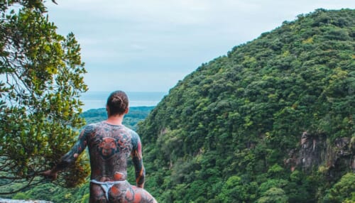 Mann mit Tattoos im Dschungel.