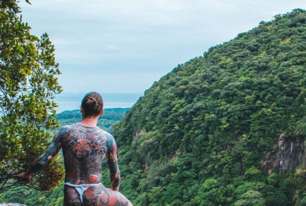 Mann mit Tattoos im Dschungel.